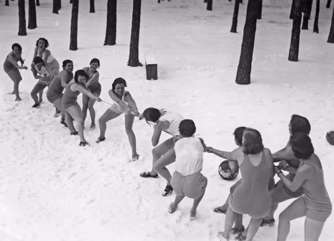 Tug of war wintertime. Two teams of women in bathingsuits are having a tug of war in the snow. 1930s