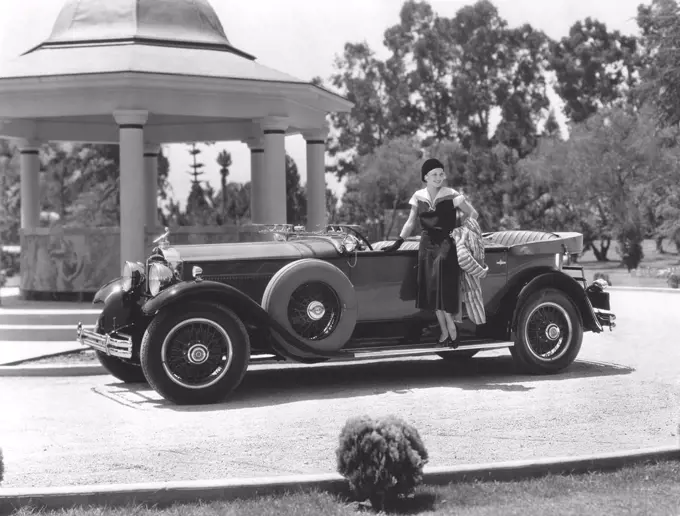 American car in the 1930s. A young Hollywood woman poses on the elegant new Packard car. 1930s