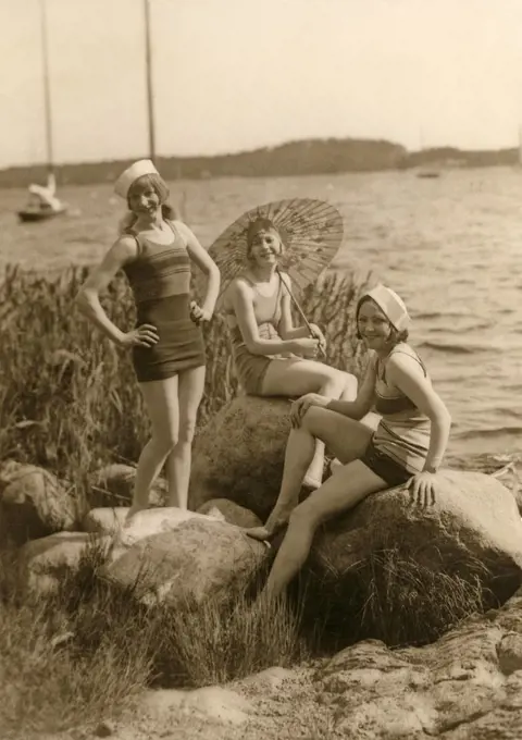 Having fun in the 1930s. Three young women on the beach dressed in the 1930s fashion of bathing suits. The fabric was cotton then. Sweden 1930s