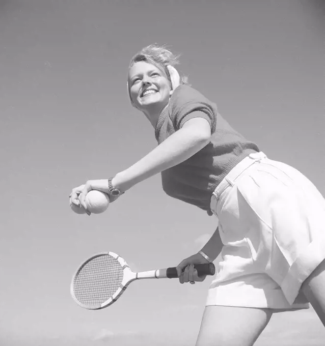 Tennis in the 1940s. The young actress and model Haide Göransson, 1928-2008, is playing tennis, dressed in proper tennis clothes. White shorts and a jumper. She stands ready to serve the ball. Sweden 1940s. Photo Kristoffersson ref U142-6