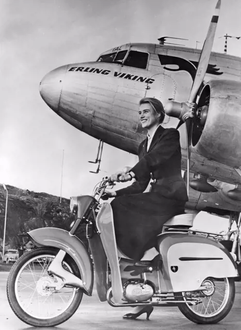 Woman of the 1950s. A young woman with a new Monark moped in front of a passenger plane. 1957