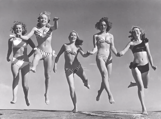 1940s summer. A group of young women in their bikinis are happy on this summer's day, jumping of joy. From left: Marianne Molander, Marianne Ljunggren, Eva Jönsson, Gunnel Wadner och Haide göransson. Photo Kristoffersson Ref AD26. Sweden 1947.