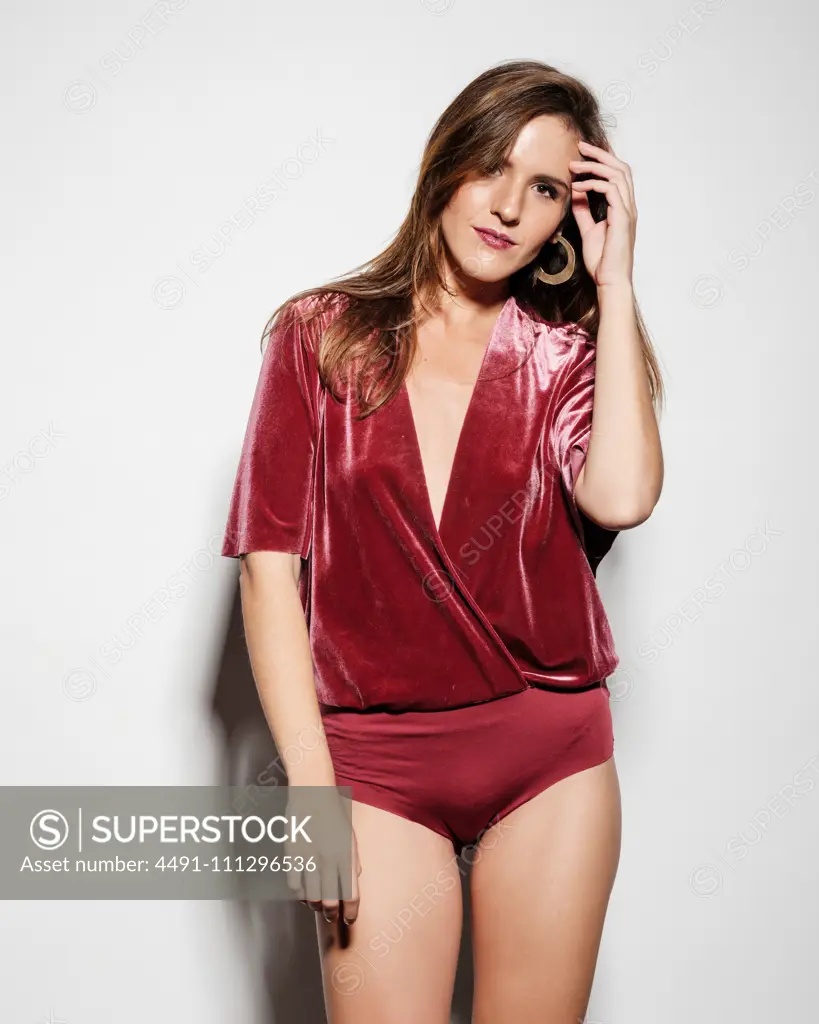 Confident young beautiful slim female model in elegant red body