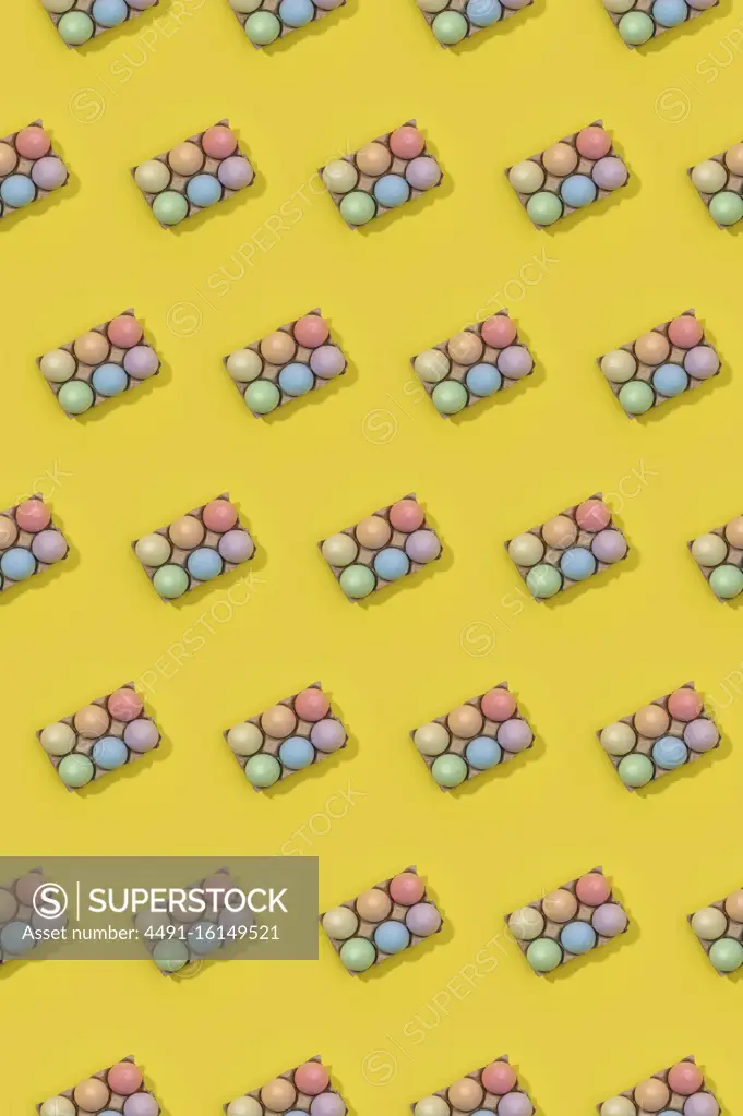 Bright seamless Easter template with white eggs in carton boxes on yellow background