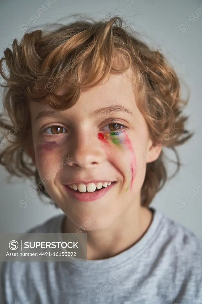 Cheerful blond boy with fading rainbow under eye smiling looking away at home during quarantine