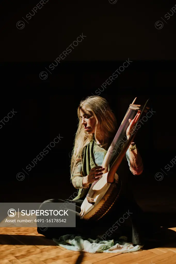 Lady playing lyre in dark room