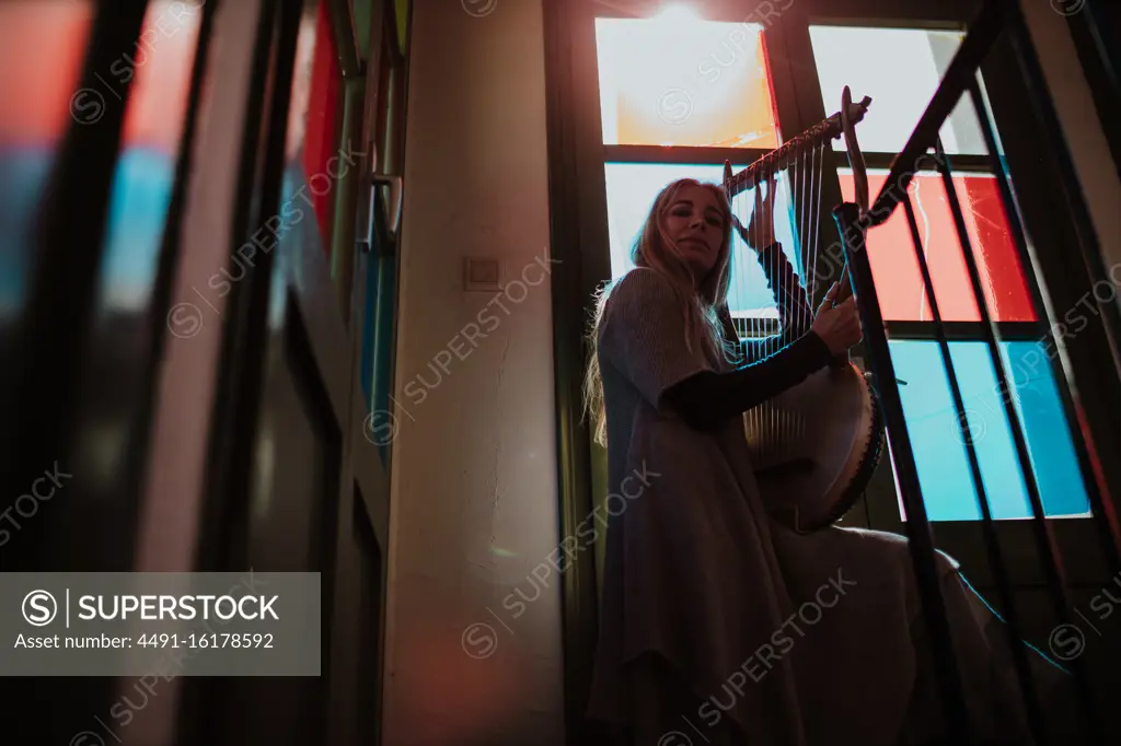 Woman with lyre standing near stained glass windows