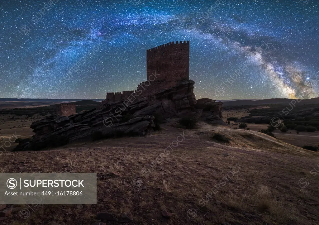 Remains of ancient castle under Milky Way at starry night with lantern light