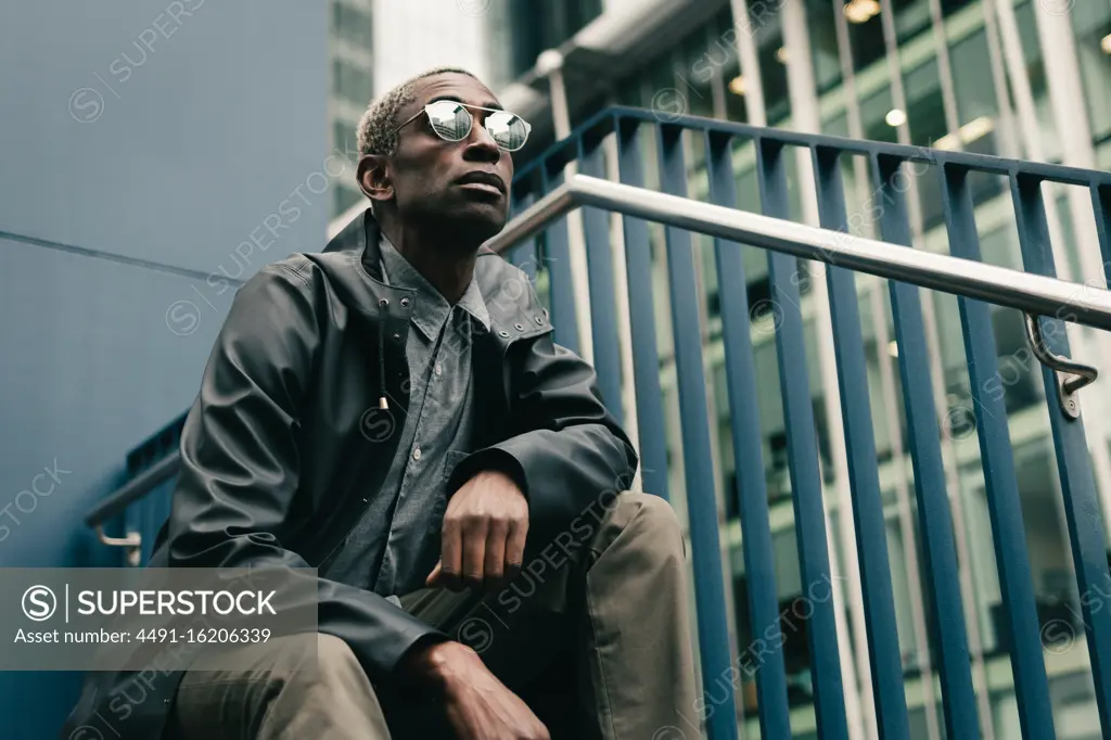 Stylish black man sitting on haunches on street