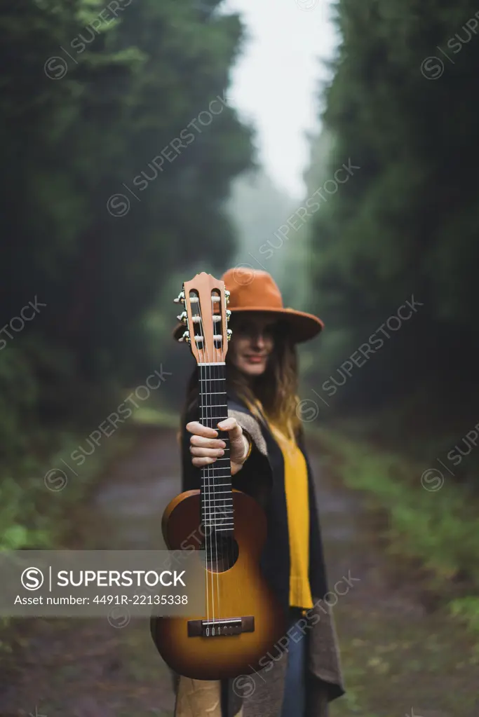 Woman showing ukelele in woods