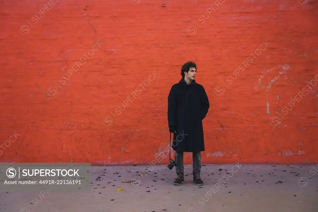 Man posing at orange wall