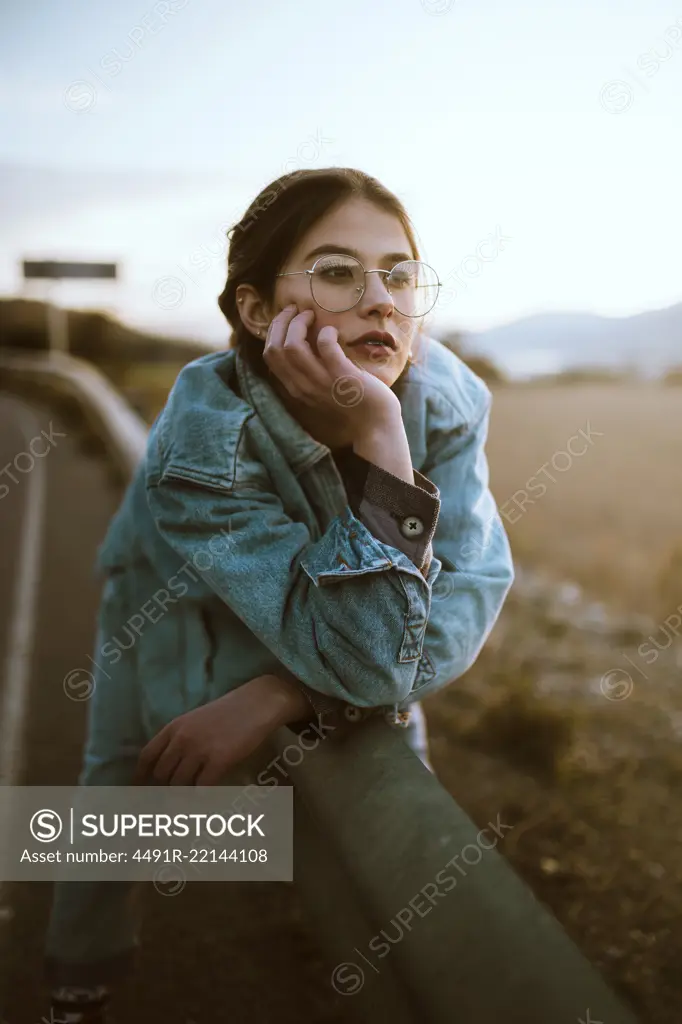 Woman leaning on fence on road