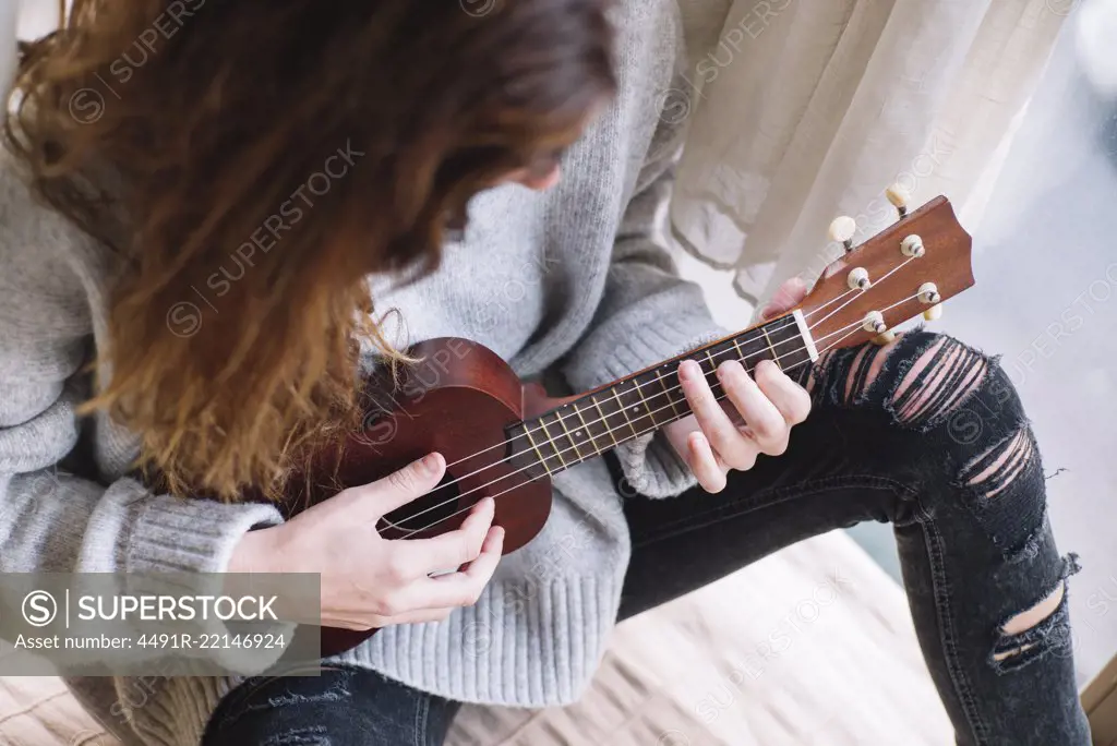 Cheerful woman playing ukulele