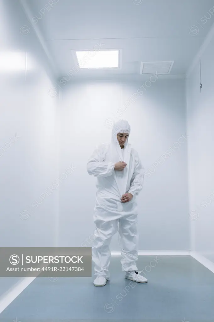 Researcher man putting on white costume before walking in lab.