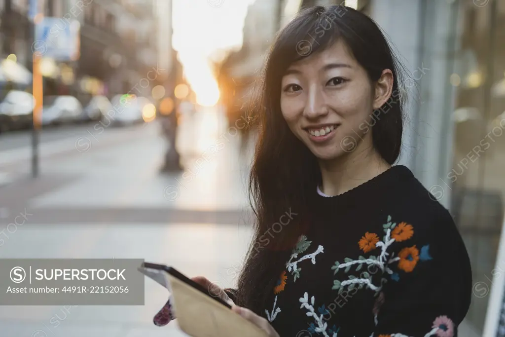 Asian woman browsing smartphone on street