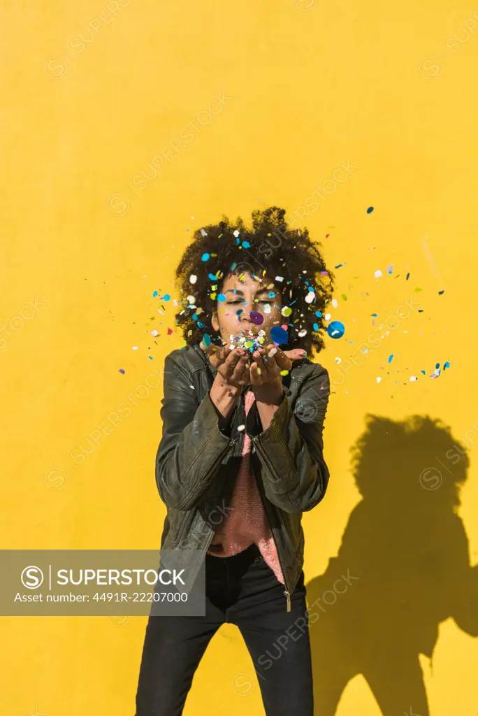 Black woman with afro hair throwing confetti to celebrate a very special day