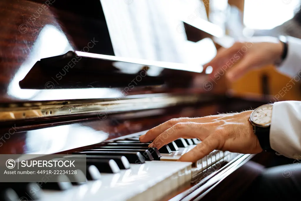 Crop side view of man hands playing piano in a music studio