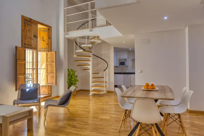 Interior of simple stylish dining room and stairs in modern duplex flat in daylight