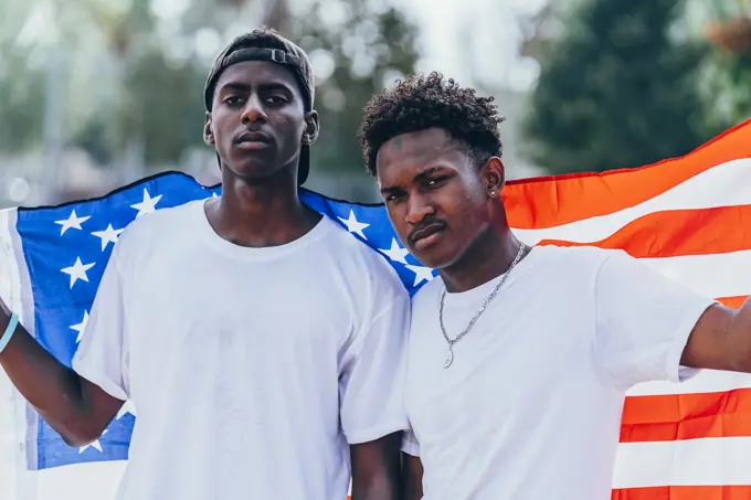 Serious African American men holding American flag on shoulder and looking away