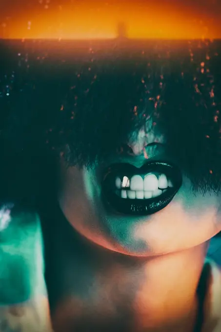 Crop female model in synthetic wig and with black lipstick showing teeth under colorful light