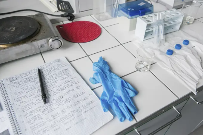 Blue gloves and notes with different equipment on table in laboratory.
