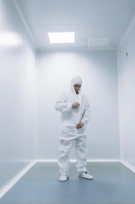 Researcher man putting on white costume before walking in lab.