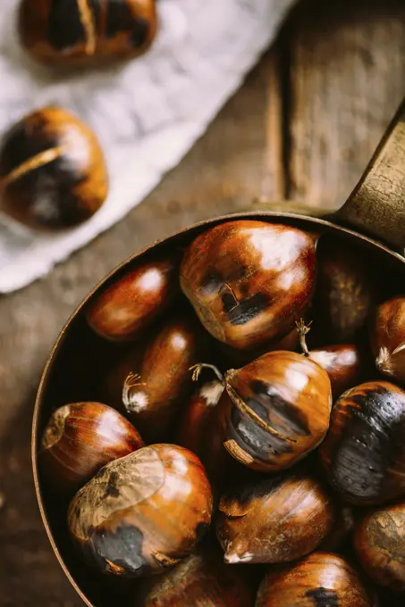 Roasted chestnuts on copper saucepan with dark wooden background