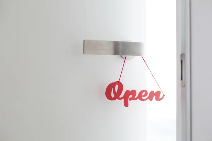 "Open" sign handmade with red letters hanged on a door knob