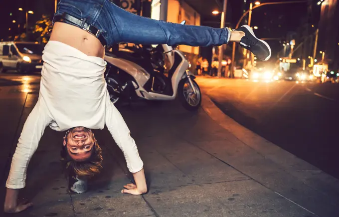 Attractive young caucasian man doing handstand in the city at night