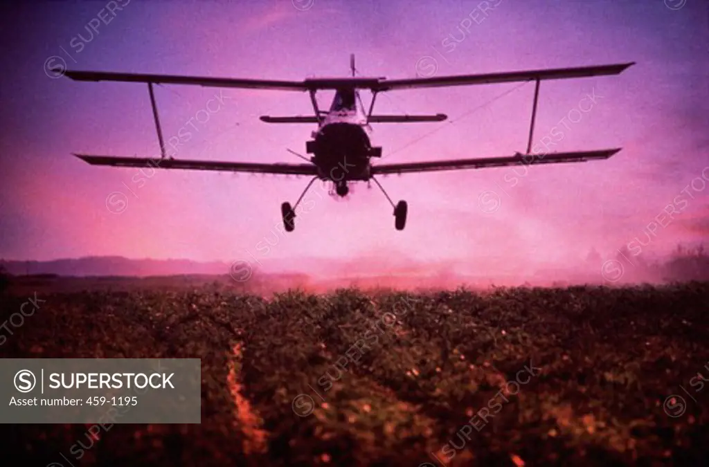 Crop dusting aircraft flying over a farm field