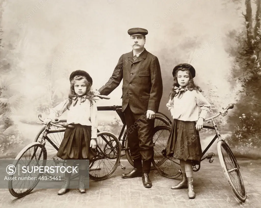 Portrait of a mature man and his two daughters standing with bicycles