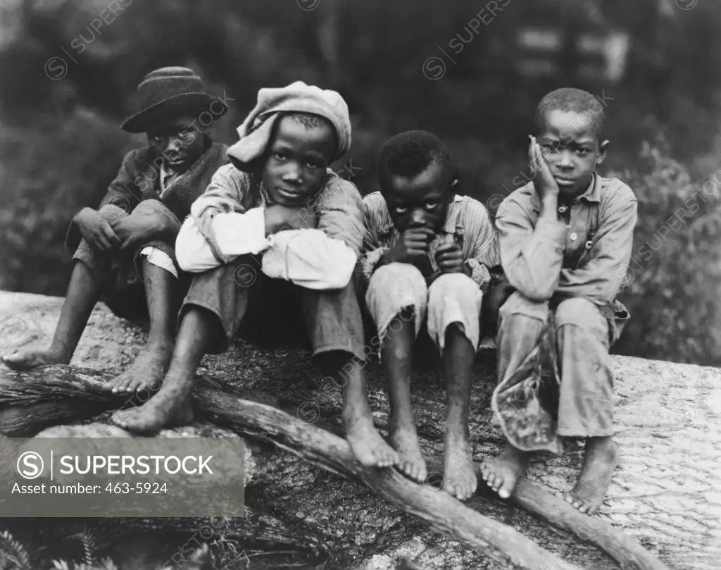 Four boys sitting on a log