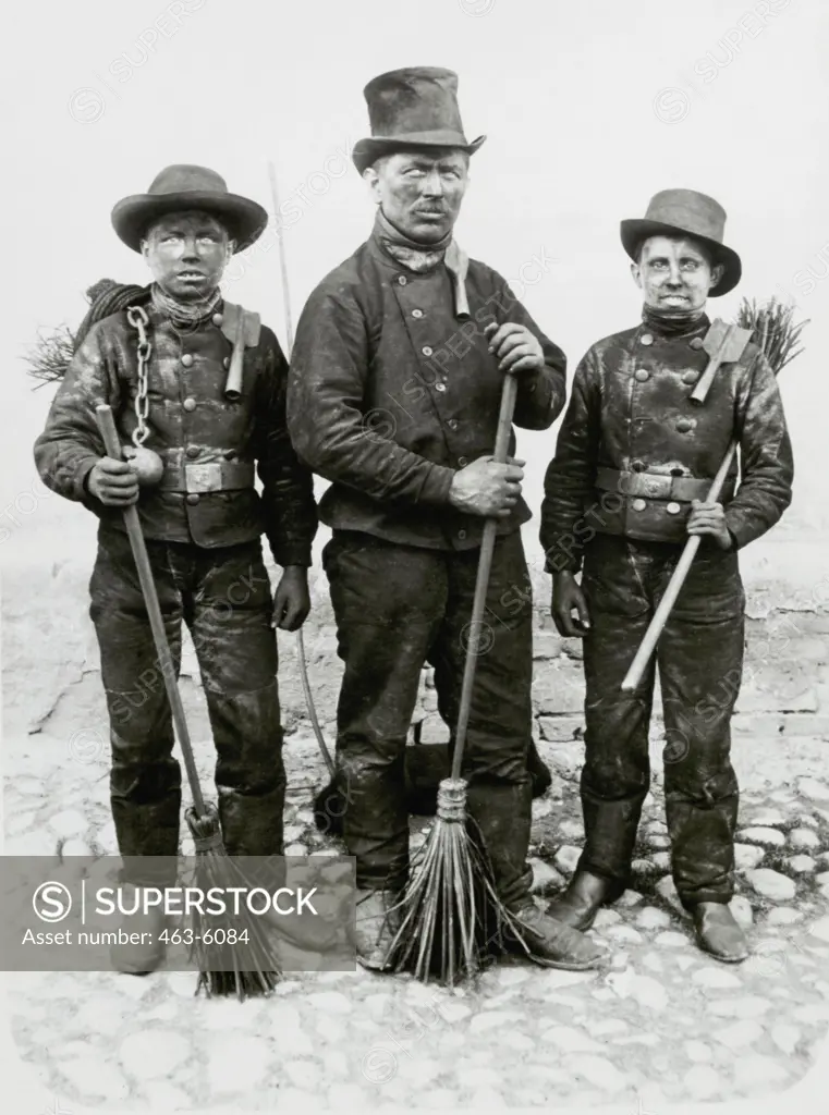Chimney sweeper with two apprentices standing with their brooms, Fraustadt, Germany, Circa 1915
