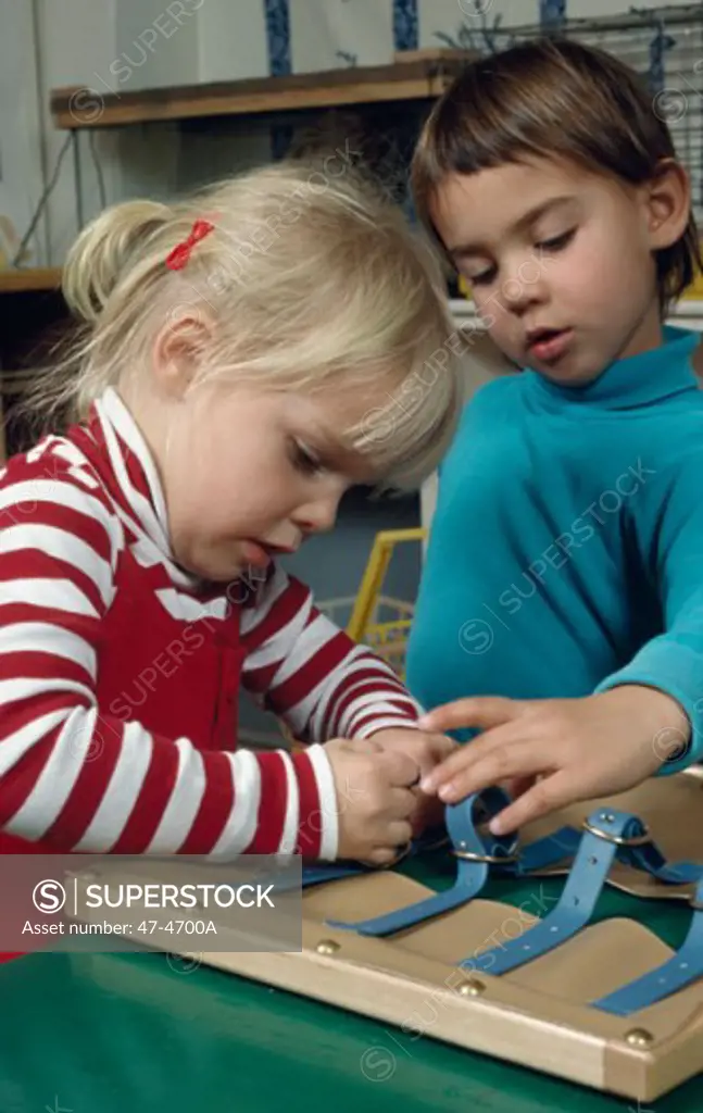 Close-up of a boy and girl fastening straps in a preschool