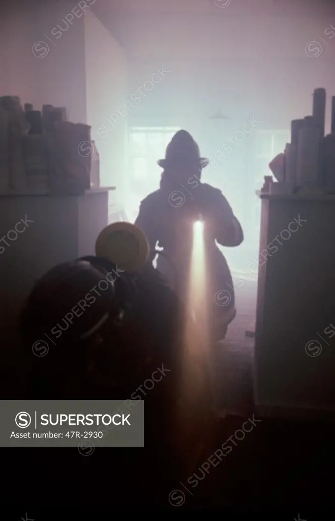 Silhouette of a firefighter holding a flashlight