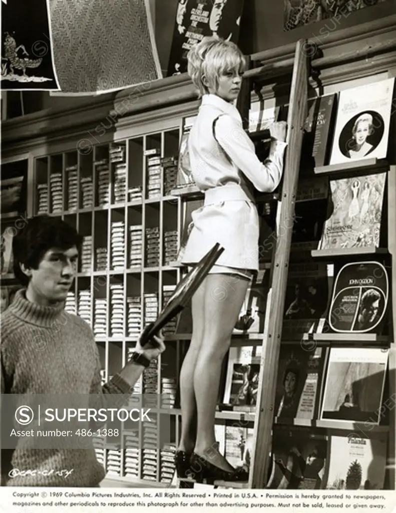 Woman climbing ladder in shop, 1969