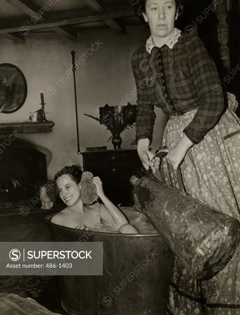 Woman takes bath while servant pours water