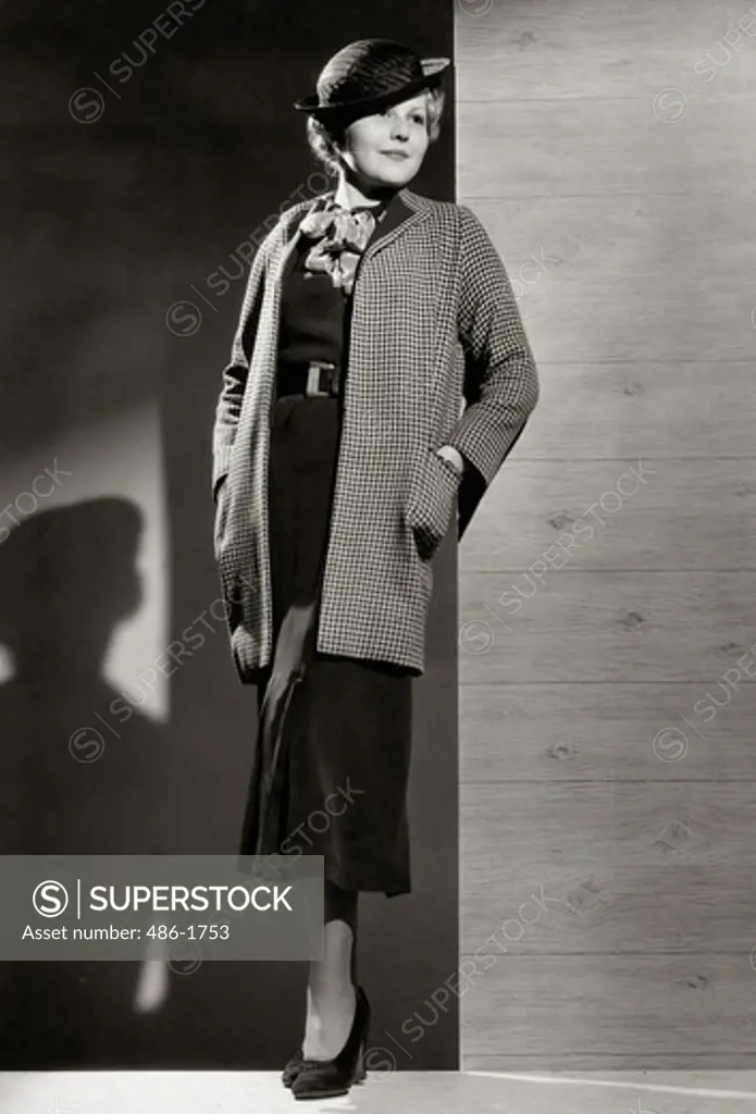 Fashion model posing by wall in autumn clothing, 1931