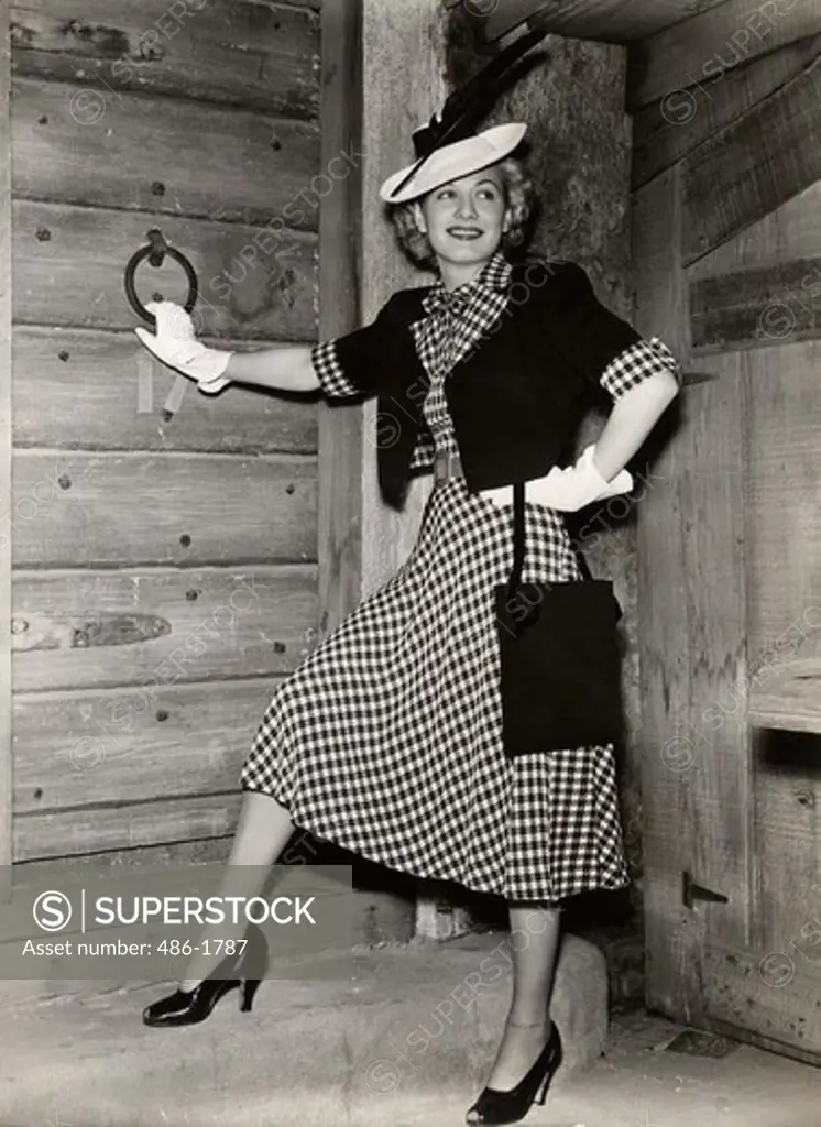 Young woman in plaid dress posing by door