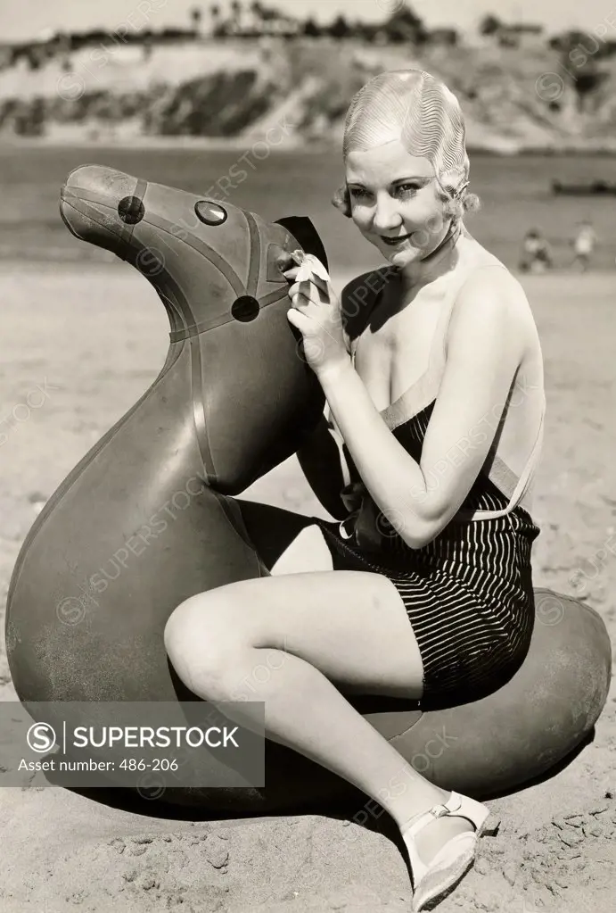 Portrait of a young woman sitting on a inflatable horse on the beach
