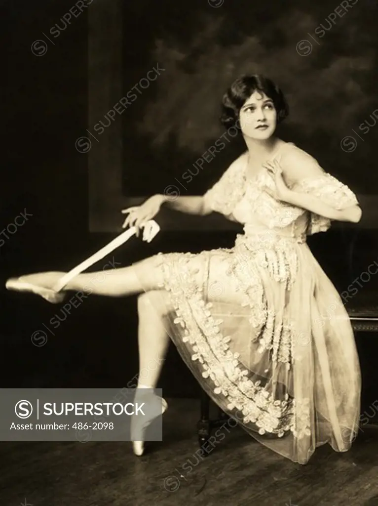 Ballet dancer holding ribbon of her ballet shoe