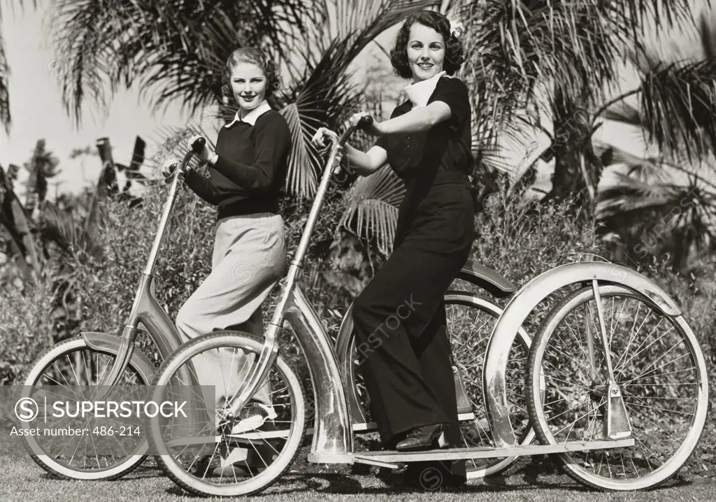 Portrait of two young women smiling with their bicycles