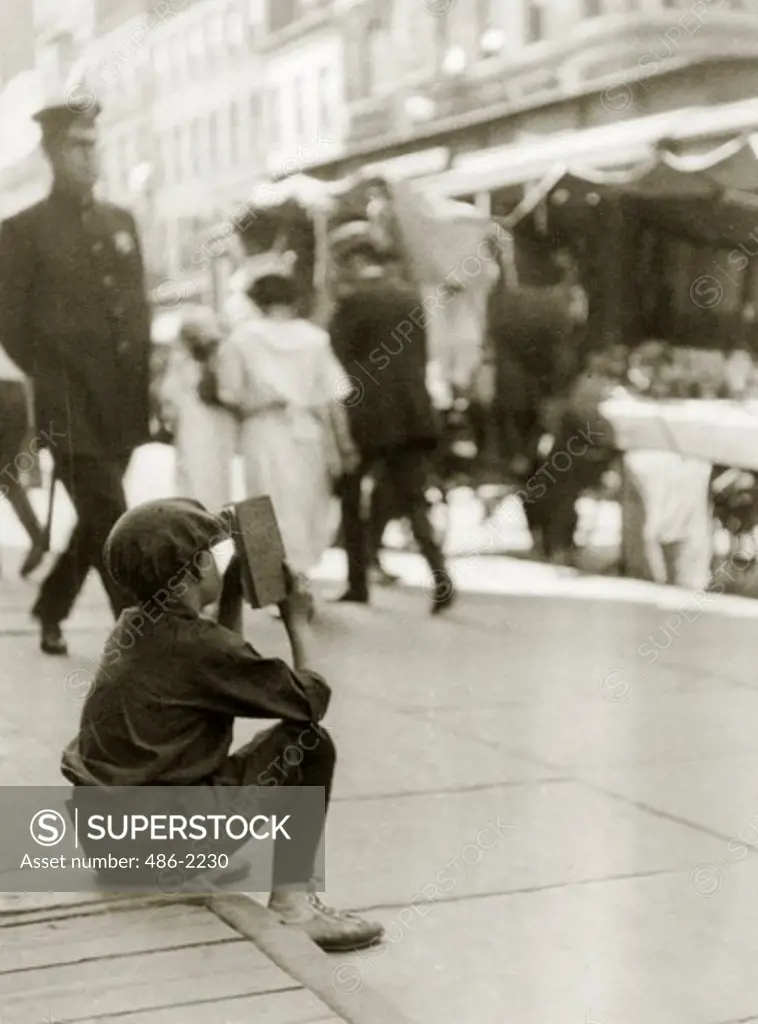 USA, New York City, East Side, Boy Sitting In Street