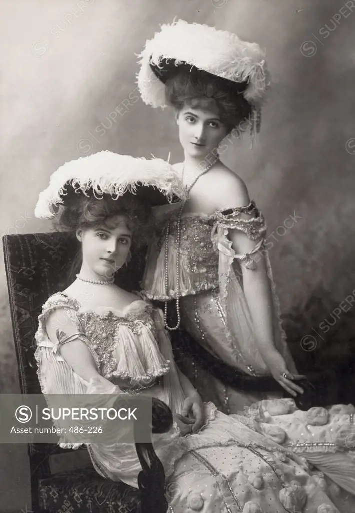 Portrait of a young woman sitting with another young woman standing by her side