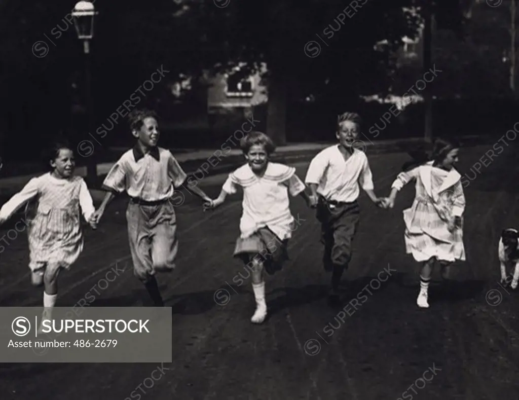 Fronr view of five children holding hands and running