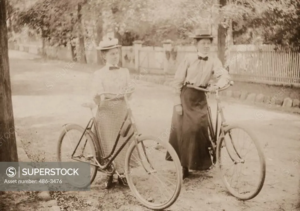 Two women with bikes on road