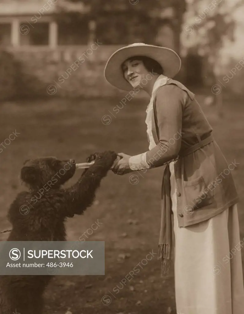 Portrait of woman holding milk bottle for bear cub