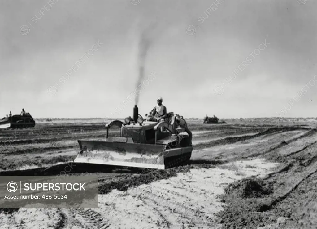Pakistan, Punjab, Thal desert, Man on tractor, 1957, Three International crawler tractors level land for use of large contingent of farmers coming into Thal region, 1957