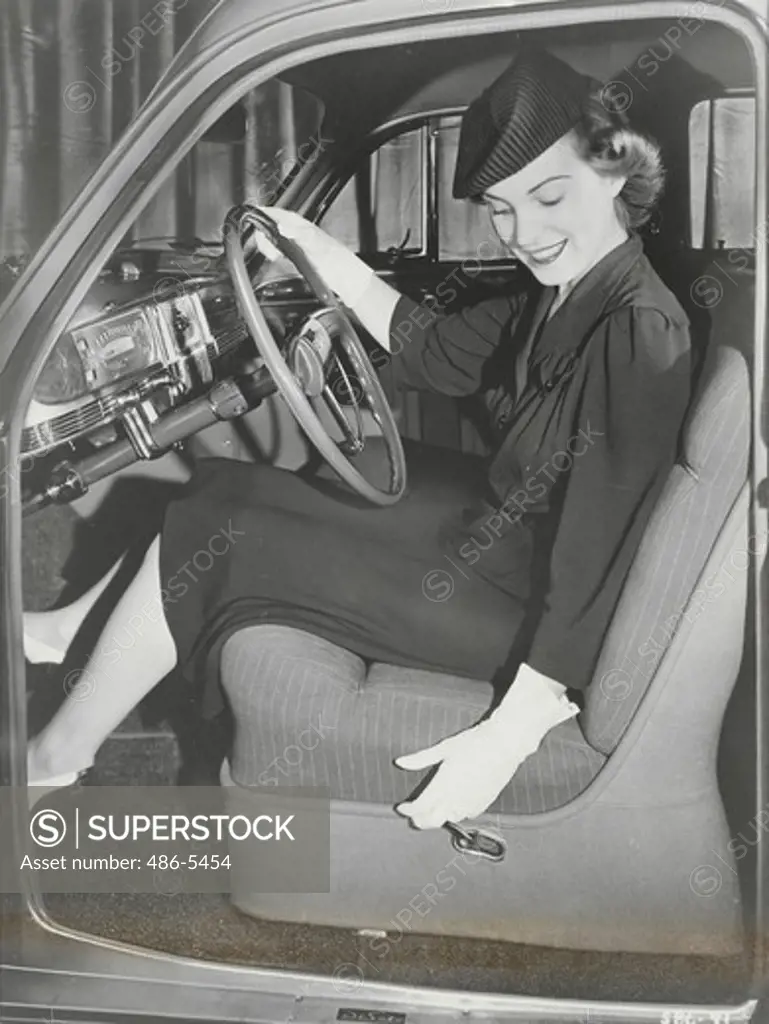Young woman sitting in De Soto car, 1941, Front seat adjustment control on De Soto has been improved in 1941 with easily operated lever, Instead of smaller button previously used