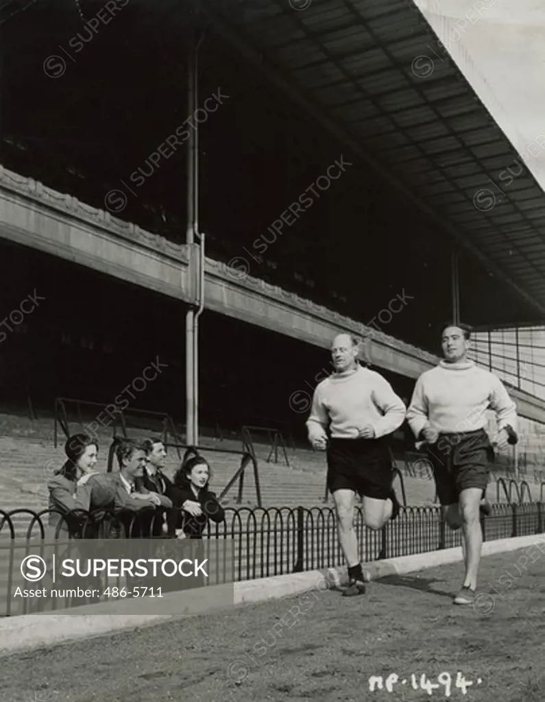 UK, London, Holloway, Hazel Court and Zena Marshall at Arsenal Stadium, Hazel Cour, Peter Murray (J. Arthur Rank Organization ltd contract artiste), Ted Drake, famous player of yesteryear and now Arsenal coach. Watch George Male, Arsenal's capitan and Denis Compton, popular all-rounder, during a trot round the field.
